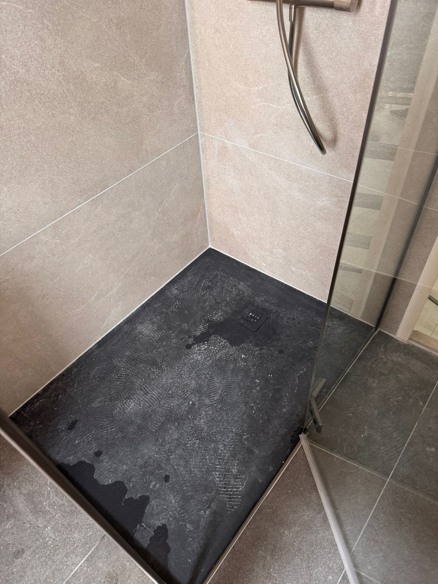 Douchevloer met zwarte leisteenlook tegels en glazen douchewand